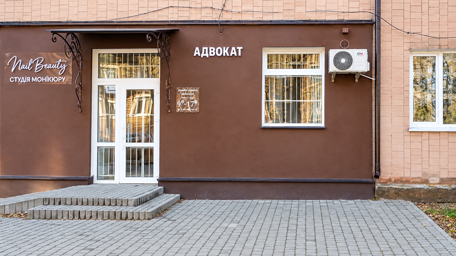 Білі засклені двері та вивіска «АДВОКАТ» праворуч від входу